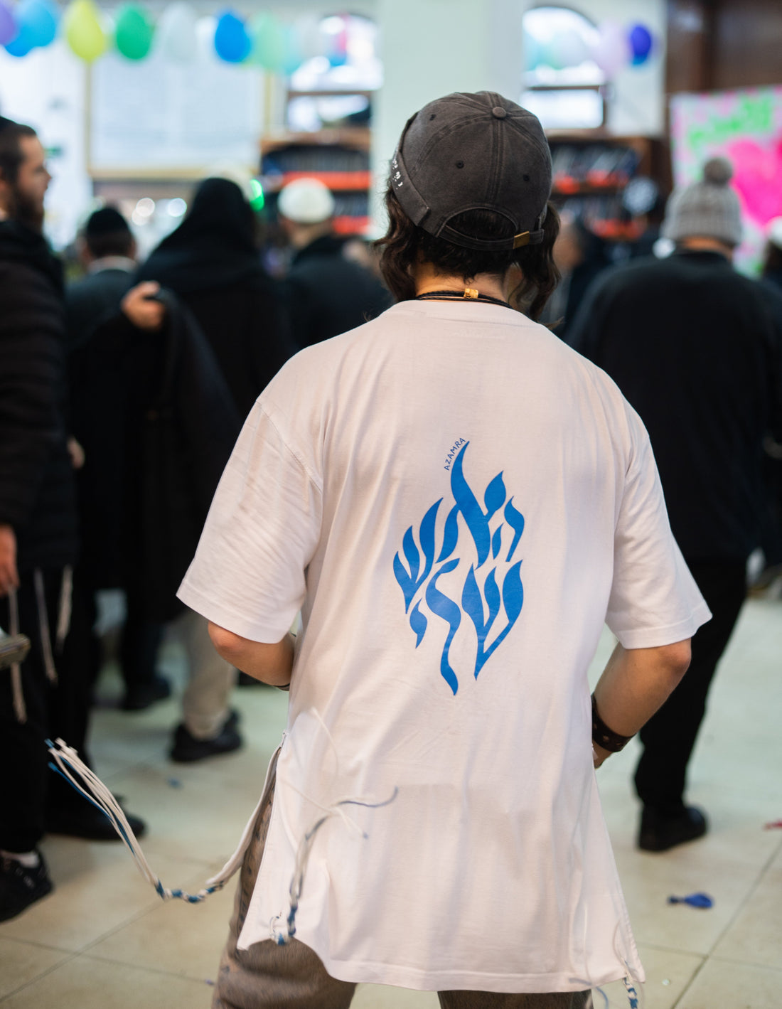 Hassid Breslev vu de dos portant un t-shirt bleu Aesh Sheli Toukad – feu de Rabbi Nahman
